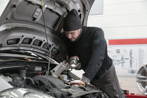 Image showing a mechanic inspecting a car engine.